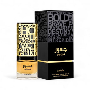 A bottle of Lattafa's Jasoor EDP Perfume 3.4 oz/100 ml is placed next to its sleek black box. The bottle boasts bold golden lettering and contains a yellow liquid. The box is adorned with motivational words like "Courageous" and "Fearless" in various fonts, hinting at the sophisticated scent of this men's fragrance.