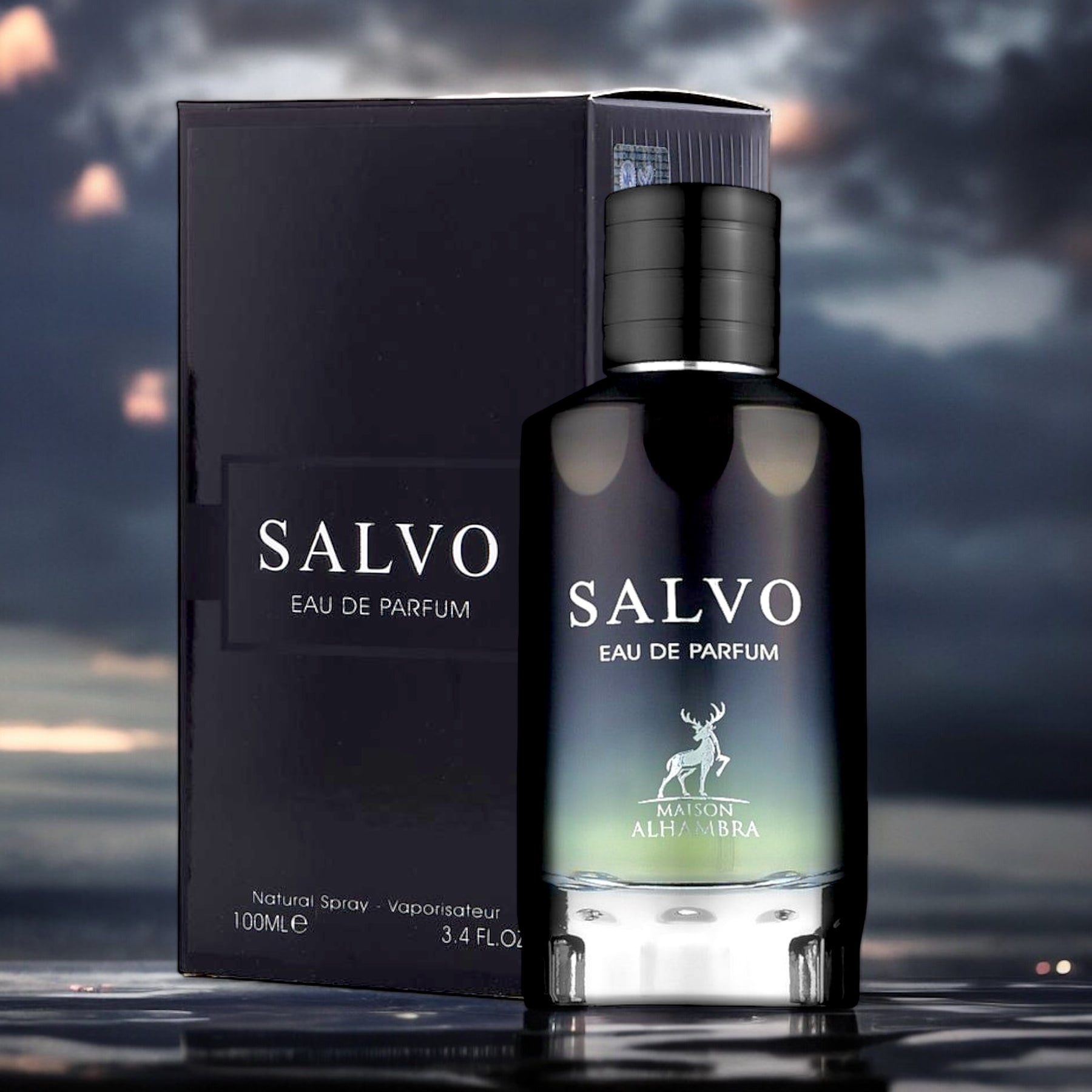 A close-up of a black bottle of "Salvo EDP Perfume for Men" by Maison Alhambra, standing in front of its matching box. The packaging, labeled "SALVO Eau De Parfum - Maison Alhambra," features a minimalist design with a stag logo and a twilight sky background, embodying modern masculinity. The bottle is 100ml (3.4 fl. oz.).