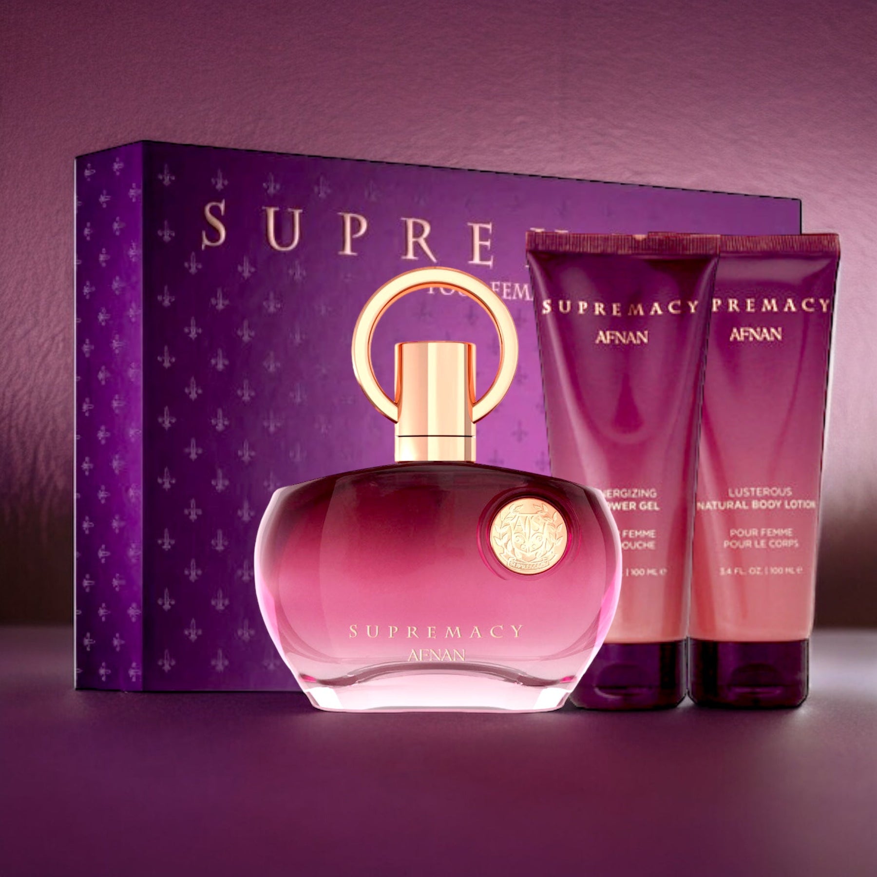 A vibrant display showcasing the Afnan Supremacy Purple Gift Set, featuring a striking purple box. The set includes a 3.4 oz/100 ml bottle of Eau de Parfum adorned with a gold ring-shaped cap, complemented by two purple tubes labeled as Energizing Shower Gel and Lustrous Natural Body Lotion, all beautifully arranged in front of the box.