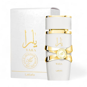 A white and gold bottle of Yara Moi EDP Perfume for Women (3.4 oz/100 ml) by Lattafa is displayed in front of its matching white and gold packaging. The bottle features elegant gold accents and the brand's name in both Arabic and English. Perfect for sophisticated women, the box has intricate designs and the Lattafa logo.